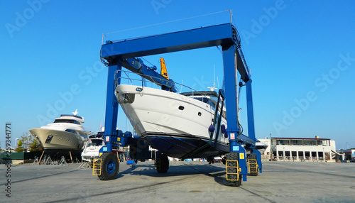 Luxury large yacht transported on a special crane for the annual repair, painting the bottom and check. Transportation industry. Sailing boat.