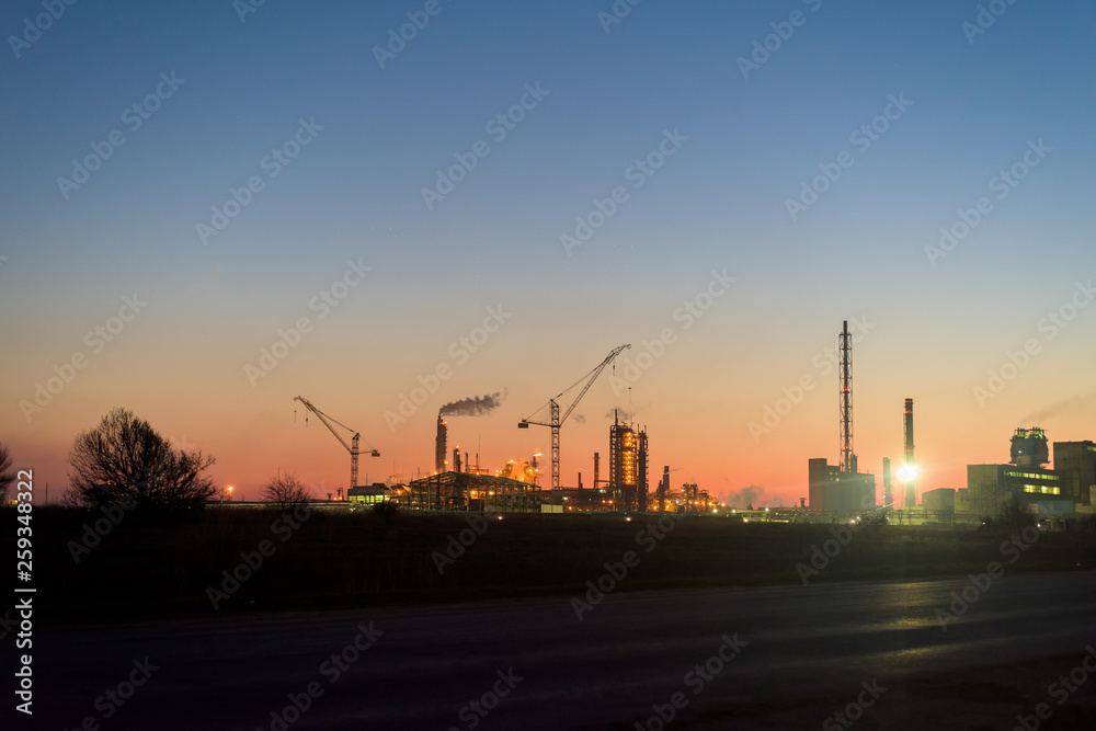 chemical plant in a silhouette image at sunset, the glowing light of the chemical industry at sunset and twilight sky, the field of chemistry