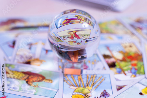 The crystal ball of predictions stands on the background of tarot cards. Blurred card background