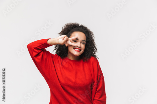 Smiling african woman in red sweater showing peace gesture