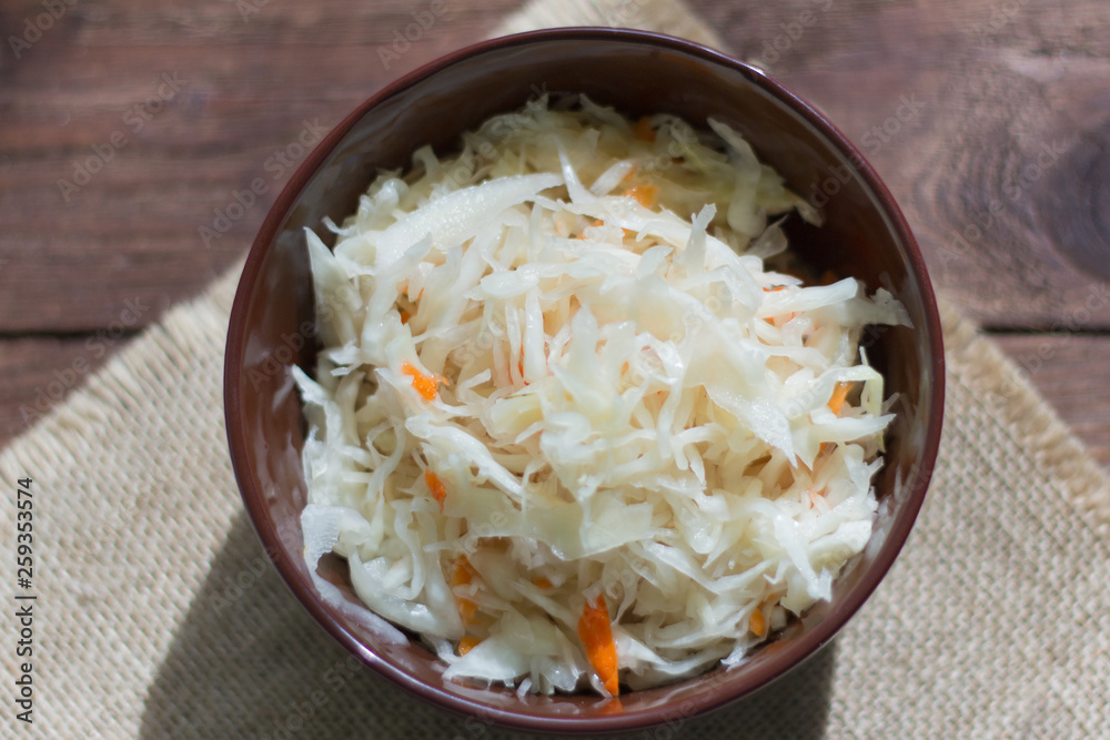 sauerkraut with carrots in a bowl on a wooden background sauerkraut with carrots in a bowl on a wooden background