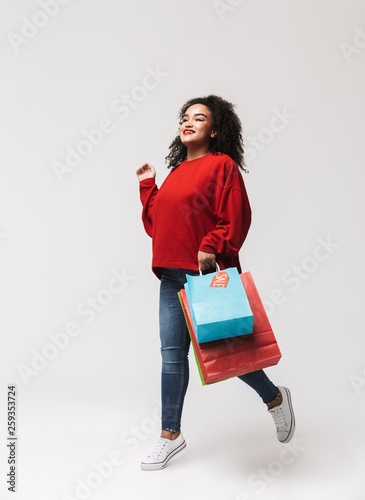 Full length image of Smiling african woman in red sweater