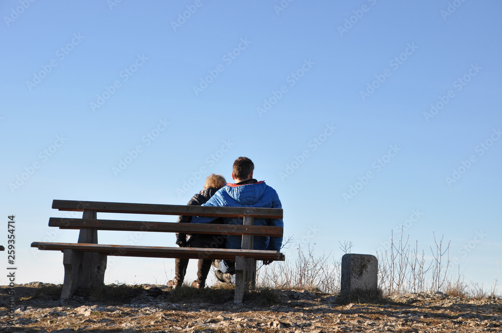 Paar auf einer Parkbank am Aussichtspunkt vor blauem Himmel Paar auf einer Parkbank am Aussichtspunkt vor blauem Himmel
