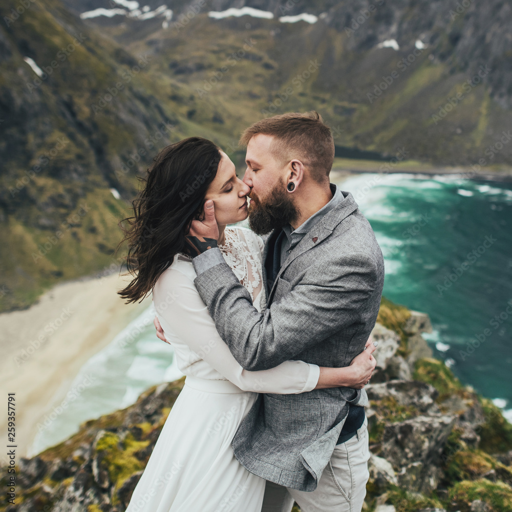 Wedding couple travelers on a hill in Norway, Kvalvika. Beautiful view of the beach, Lofoten, Norway. Wedding couple travelers on a hill in Norway, Kvalvika. Beautiful view of the beach, Lofoten, Norway.
