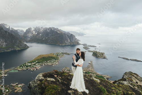 Wedding couple travelers on a hill in Norway, Kvalvika. Beautiful view of the beach, Lofoten, Norway. photo