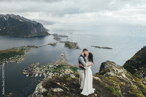 Wedding couple travelers on a hill in Norway  Kvalvika. Beautiful view of the beach  Lofoten  Norway.