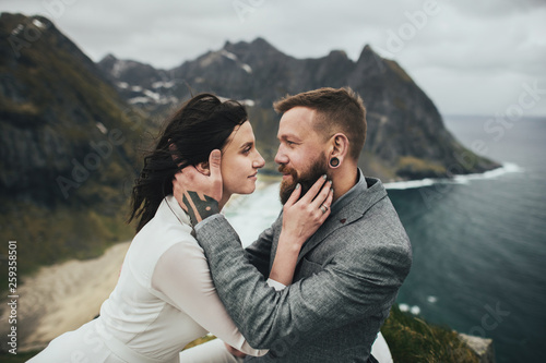 Wedding couple travelers on a hill in Norway, Kvalvika. Beautiful view of the beach, Lofoten, Norway. photo