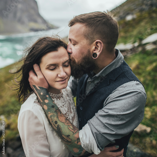 Wedding couple travelers on a hill in Norway, Kvalvika. Beautiful view of the beach, Lofoten, Norway. © Alexander