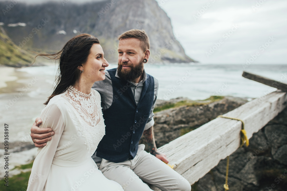 Wedding couple travelers on a hill in Norway, Kvalvika. Beautiful view of the beach, Lofoten, Norway.
