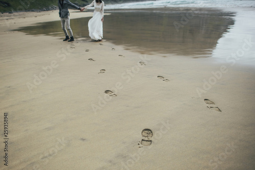 Wedding couple travelers on a hill in Norway, Kvalvika. Beautiful view of the beach, Lofoten, Norway. photo