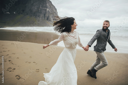 Wedding couple travelers on a hill in Norway, Kvalvika. Beautiful view of the beach, Lofoten, Norway. photo