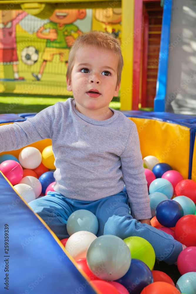 Fototapeta premium Little boy playing with colorful balls