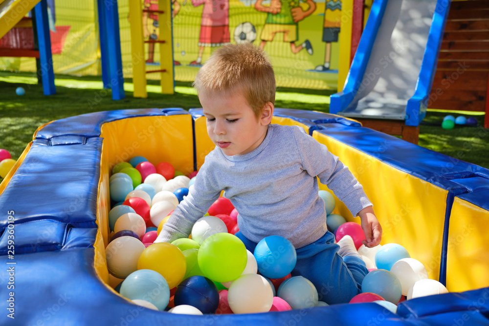Obraz premium Little boy playing with colorful balls in park playground