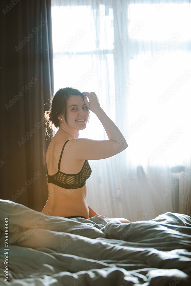 Foto de young pretty woman in black bra sitting on bed. morning time do  Stock