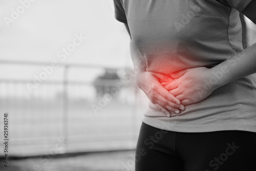 A woman is suffering stomach pain from running or workout, pain and colic is a frequent problem while running or workout. photo