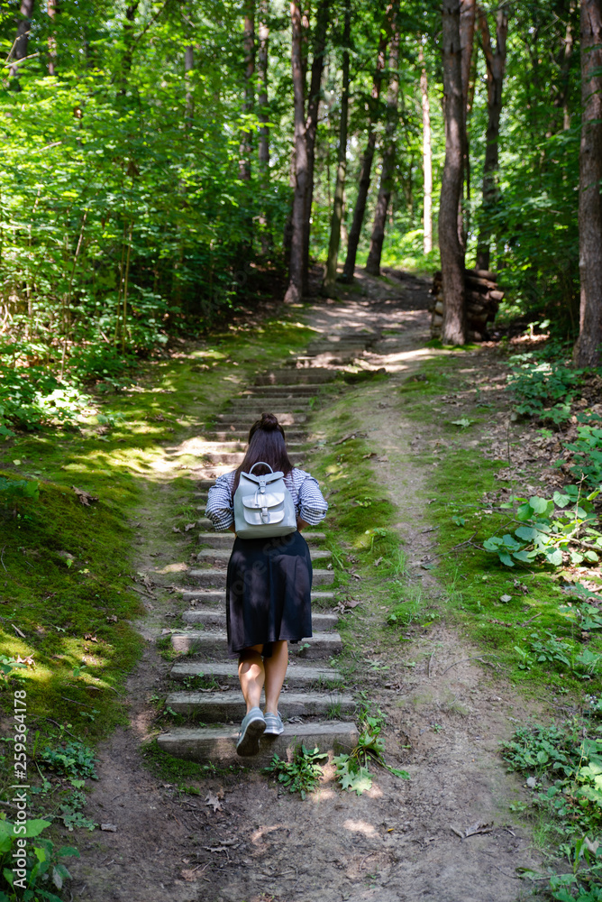 Obraz premium woman walking up by old stairs in forest
