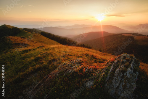 Sunset in the mountains with warm light and beautiful view to mountains in the fog. Ukraine, Carpathians Borjava Ridge