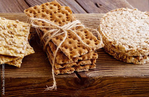 Three types of diet bread. Round buckwheat crispbread, wheat crispbread and crispbread with sunflowe on wooden vintage cutting board and textured background.