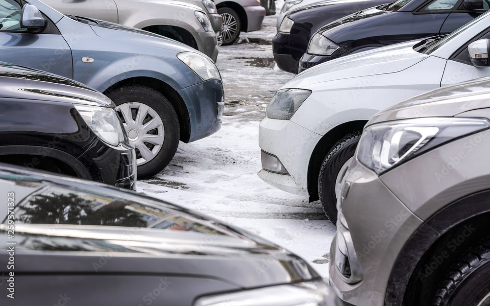 Cars parked in snow covered parking lot, detail on front bumper headlights and tires only Cars parked in snow covered parking lot, detail on front bumper headlights and tires only