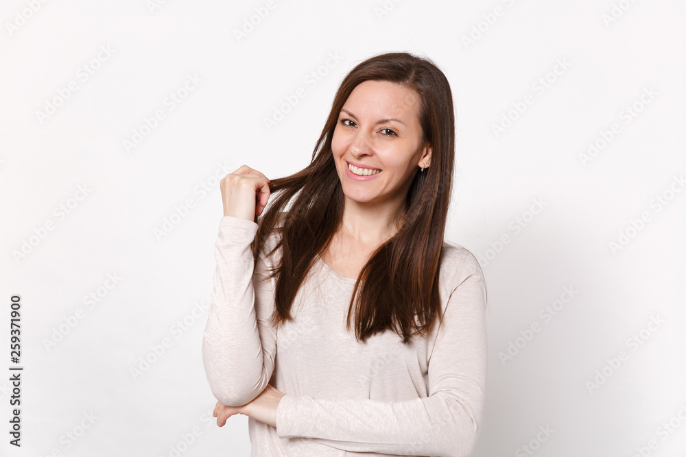 Portrait of attractive smiling young woman in light clothes looking camera, holding hair isolated on white wall background in studio. People sincere emotions, lifestyle concept. Mock up copy space. Portrait of attractive smiling young woman in light clothes looking camera, holding hair isolated on white wall background in studio. People sincere emotions, lifestyle concept. Mock up copy space.