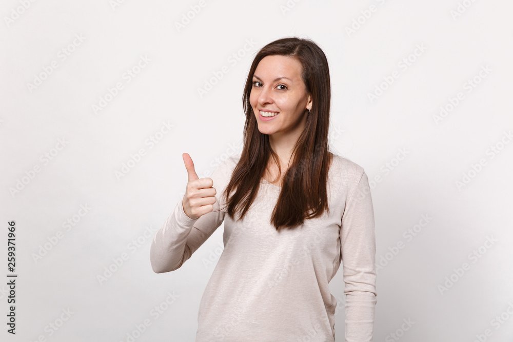 Portrait of smiling pretty young woman in light clothes looking camera, showing thumb up isolated on white wall background in studio. People sincere emotions, lifestyle concept. Mock up copy space. Portrait of smiling pretty young woman in light clothes looking camera, showing thumb up isolated on white wall background in studio. People sincere emotions, lifestyle concept. Mock up copy space.