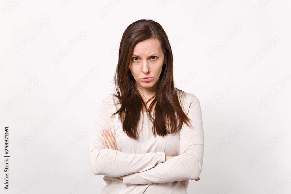 Portrait of serious strict young woman in light clothes looking camera holding hands crossed isolated on white wall background in studio. People sincere emotions lifestyle concept. Mock up copy space. Portrait of serious strict young woman in light clothes looking camera holding hands crossed isolated on white wall background in studio. People sincere emotions lifestyle concept. Mock up copy space.