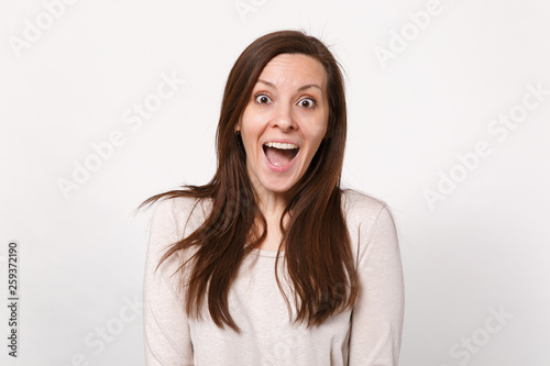 Portrait of surprised excited beautiful young woman in light clothes keeping mouth wide open isolated on white wall background in studio. People sincere emotions lifestyle concept. Mock up copy space.