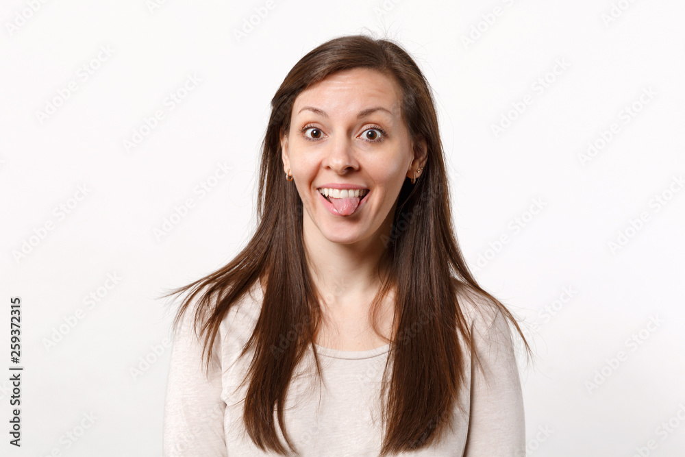 Portrait of cheerful funny crazy young woman in light clothes looking camera showing tongue isolated on white wall background in studio. People sincere emotions, lifestyle concept. Mock up copy space. Portrait of cheerful funny crazy young woman in light clothes looking camera showing tongue isolated on white wall background in studio. People sincere emotions, lifestyle concept. Mock up copy space.