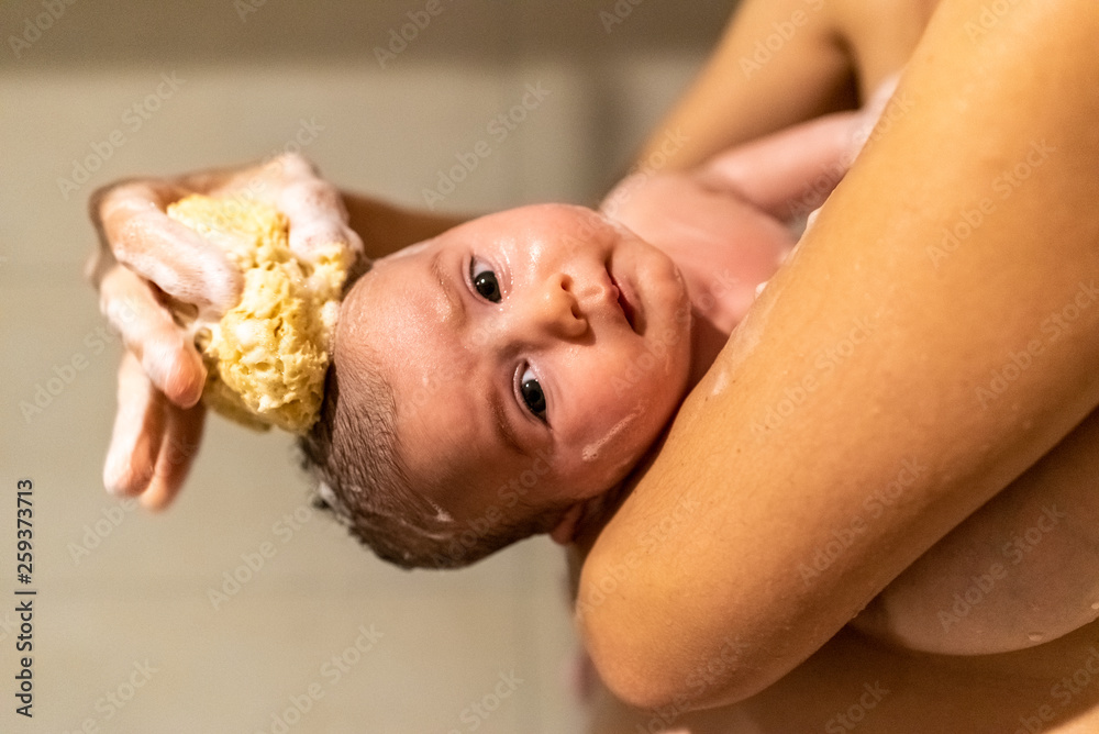Φωτογραφία Care of newborns, sponge with special natural soap for baby hygiene, washing the head of a baby girl