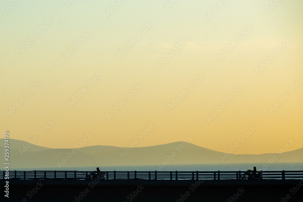 Motorcycle on the highway bridge during the dawn against the backdrop of mountains and the sea