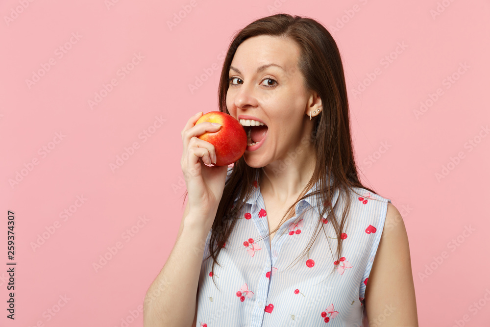 Pretty young woman in summer clothes hold biting fresh ripe red apple fruit isolated on pink pastel wall background, studio portrait. People vivid lifestyle relax vacation concept. Mock up copy space. Pretty young woman in summer clothes hold biting fresh ripe red apple fruit isolated on pink pastel wall background, studio portrait. People vivid lifestyle relax vacation concept. Mock up copy space.