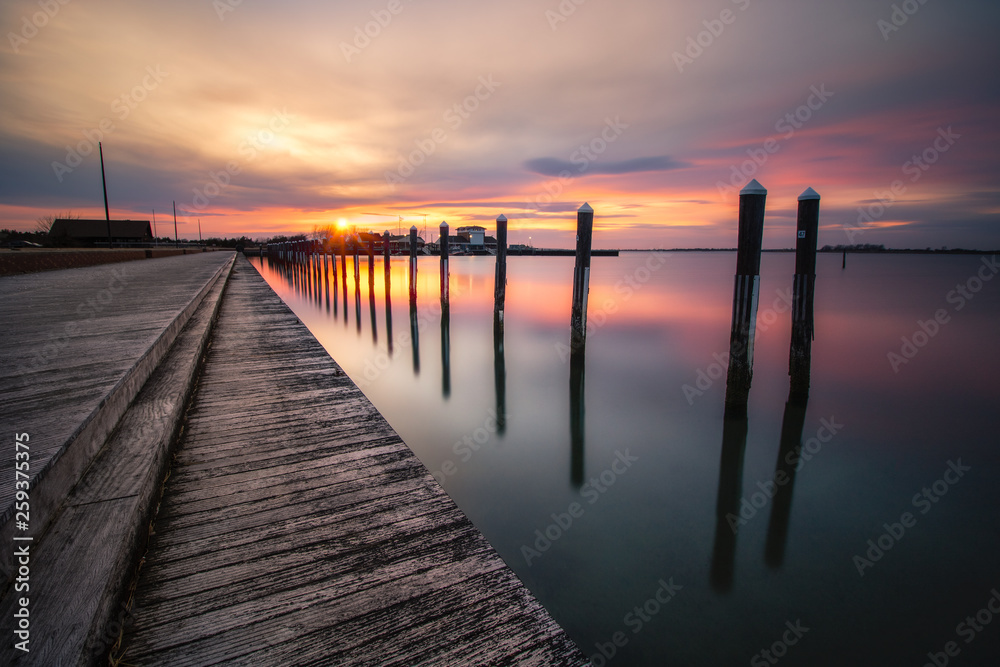 Sunset over an empty fishing pier and boat basin. Beautiful golden colors reflecting on calm still water. Long Island New York. 