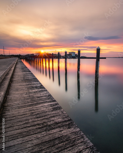 Sunset over an empty fishing pier and boat basin. Beautiful golden colors reflecting on calm still water. Long Island New York. 