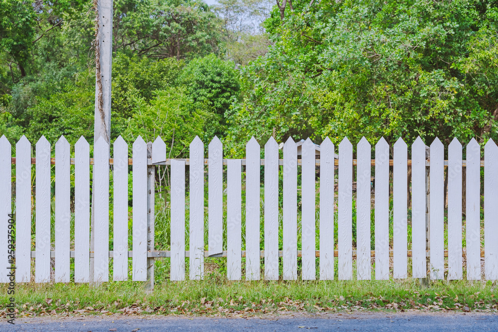 Old white wooden fence with a broken board at the roadside area Old white wooden fence with a broken board at the roadside area