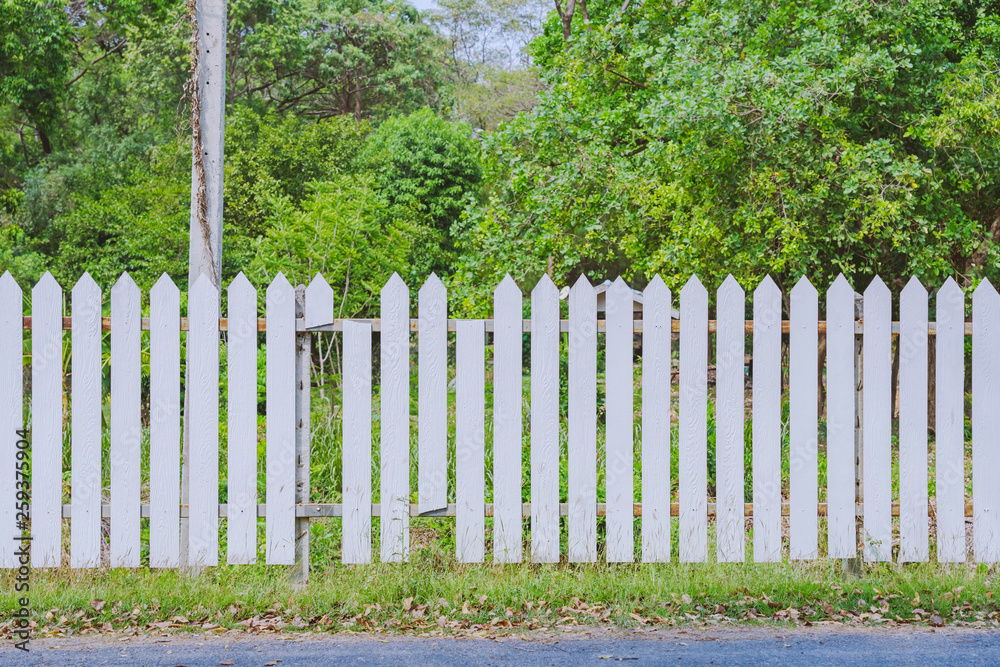 Old white wooden fence with a broken board at the roadside area