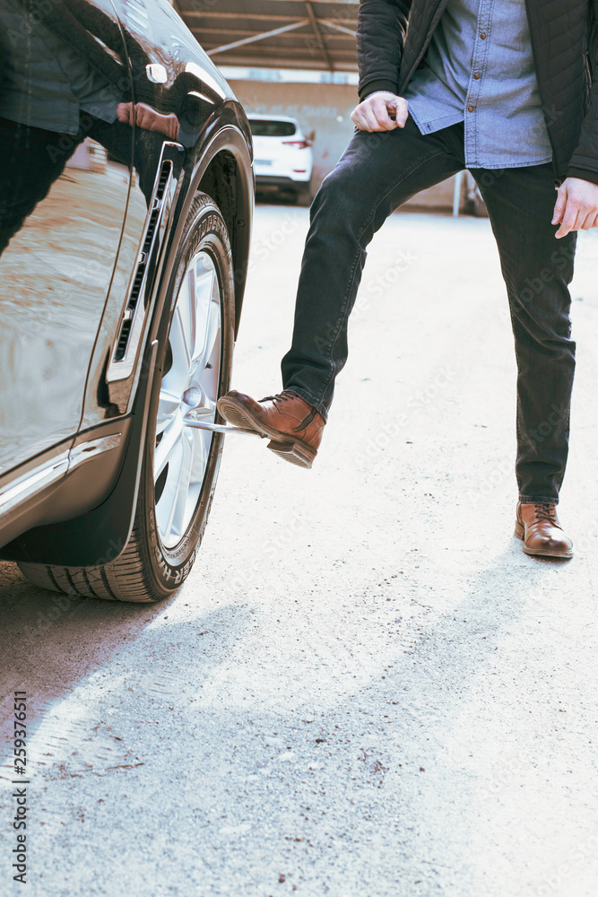 Obraz premium Man tightens lug nuts of a car. Safe driving concept.