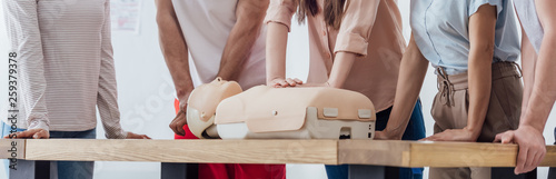 panoramic shot of group of people performing cpr on dummy during first aid training photo