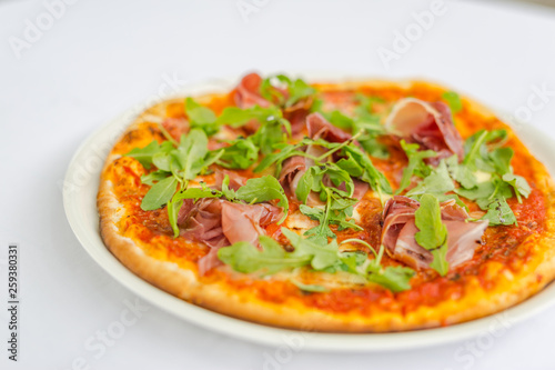 Pepperoni pizza with salami and cheese and rucola salad. TOP VIEW Tasty traditional pepperoni pizza on board on white table with decoration. Copy space for your logo. Ideal for commercial 