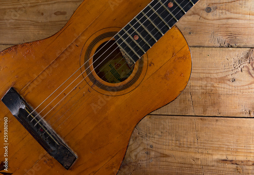 Old vintage guitar on wooden background.