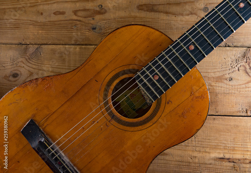 Old vintage guitar on wooden background.