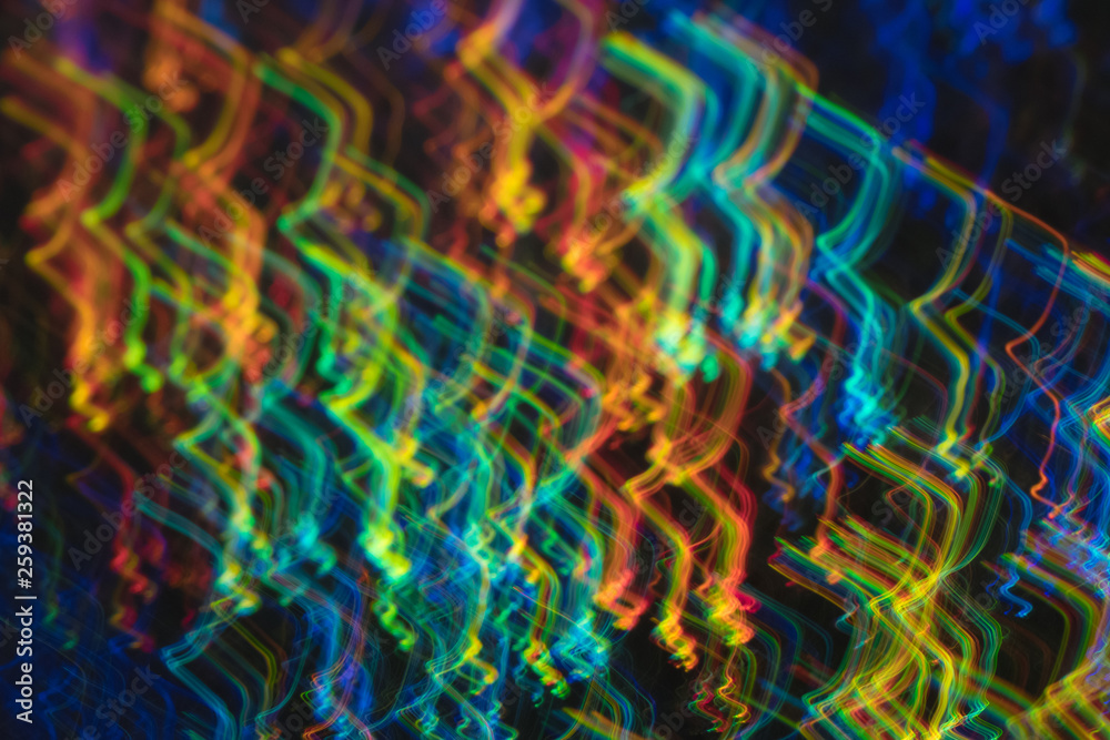 Glowing multicolor angled lines on dark background. Blurred neon lights. Lens flare effect.