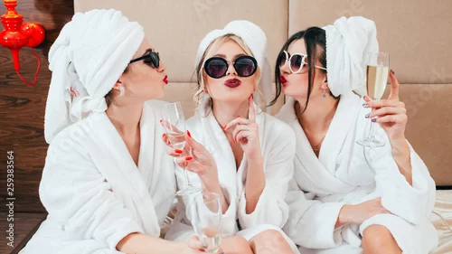 Obraz Impreza uroczystości w spa. Gratulacje dla przyjaciół. Młode kobiety z szampanem. Okulary przeciwsłoneczne, szlafroki i turbany włączone.