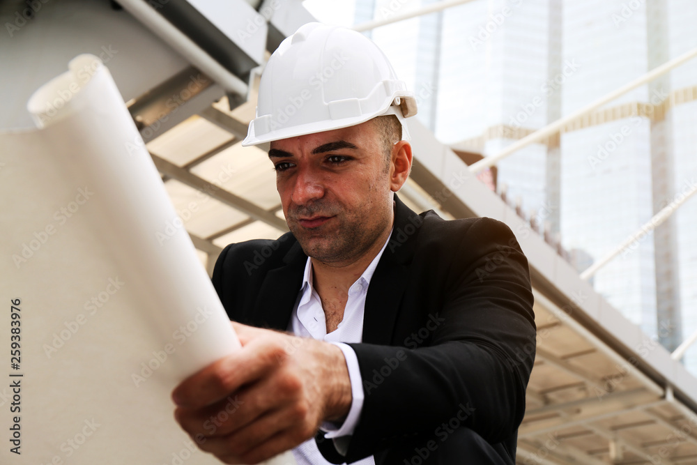 Close-up engineering man looking structure plan on paper at outdoor and building background. Close-up engineering man looking structure plan on paper at outdoor and building background.