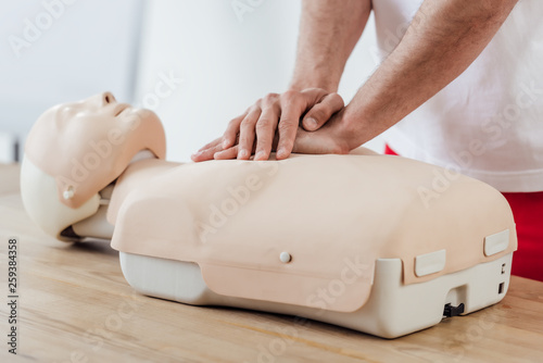 Obraz na płótnie partial view of man using chest compression technique on dummy during cpr training