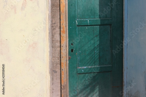 Green wooden door and a yellow wall background (Ari Atoll, Maldives)