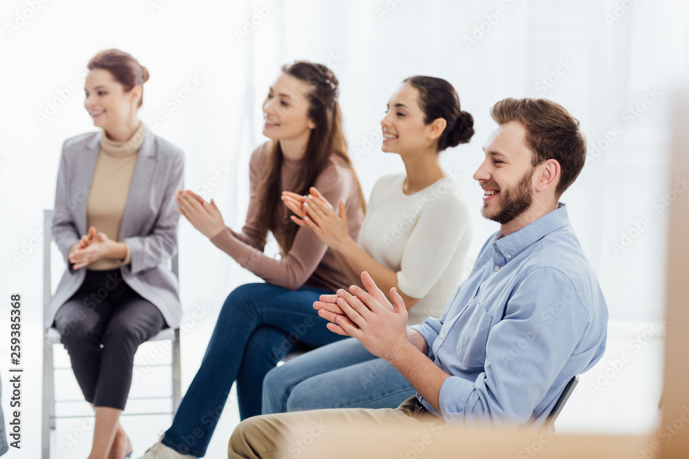 smiling group of people sitting and applauding during support group session smiling group of people sitting and applauding during support group session