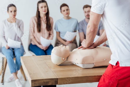 Fotografie back view of instructor performing cpr on dummy during first aid training with g