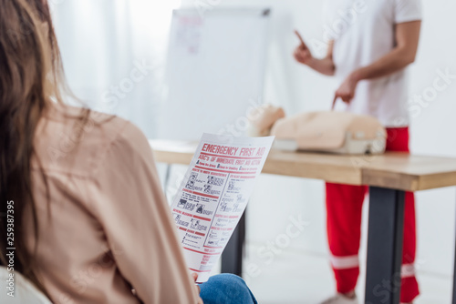 back view of woman holding first aid instruction during cpr training class photo