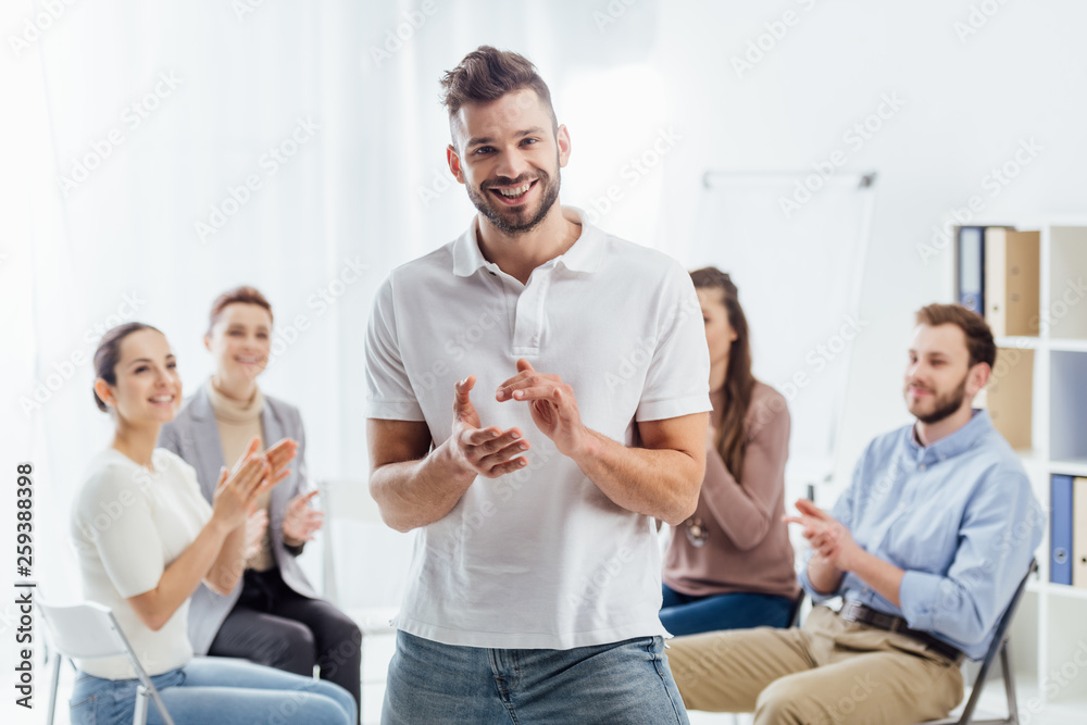 man looking at camera and applauding while people sitting during group therapy session man looking at camera and applauding while people sitting during group therapy session