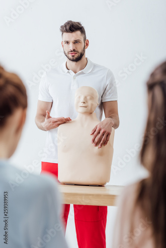 selective focus of instructor with cpr dummy during first aid training class photo